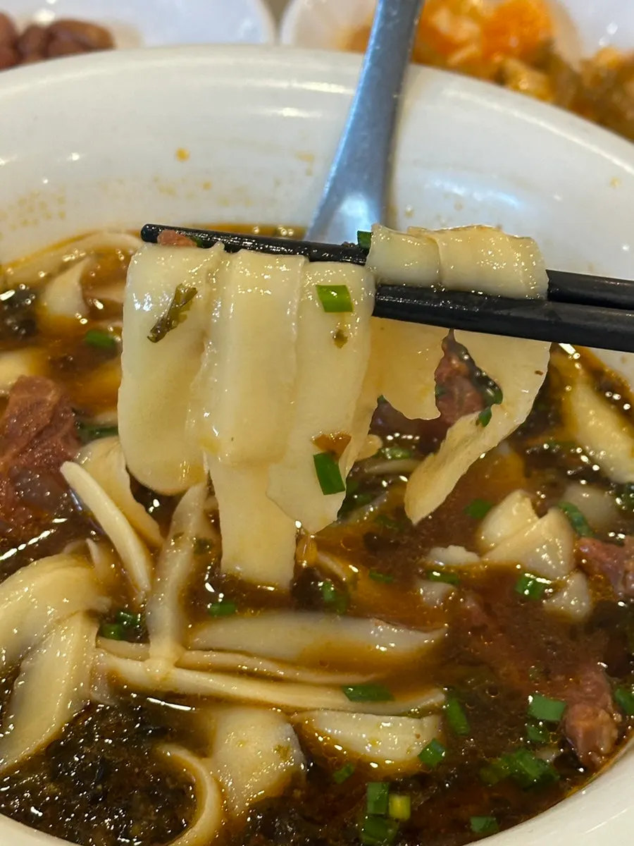 Wide dosakmyeon noodles lifted with chopsticks
