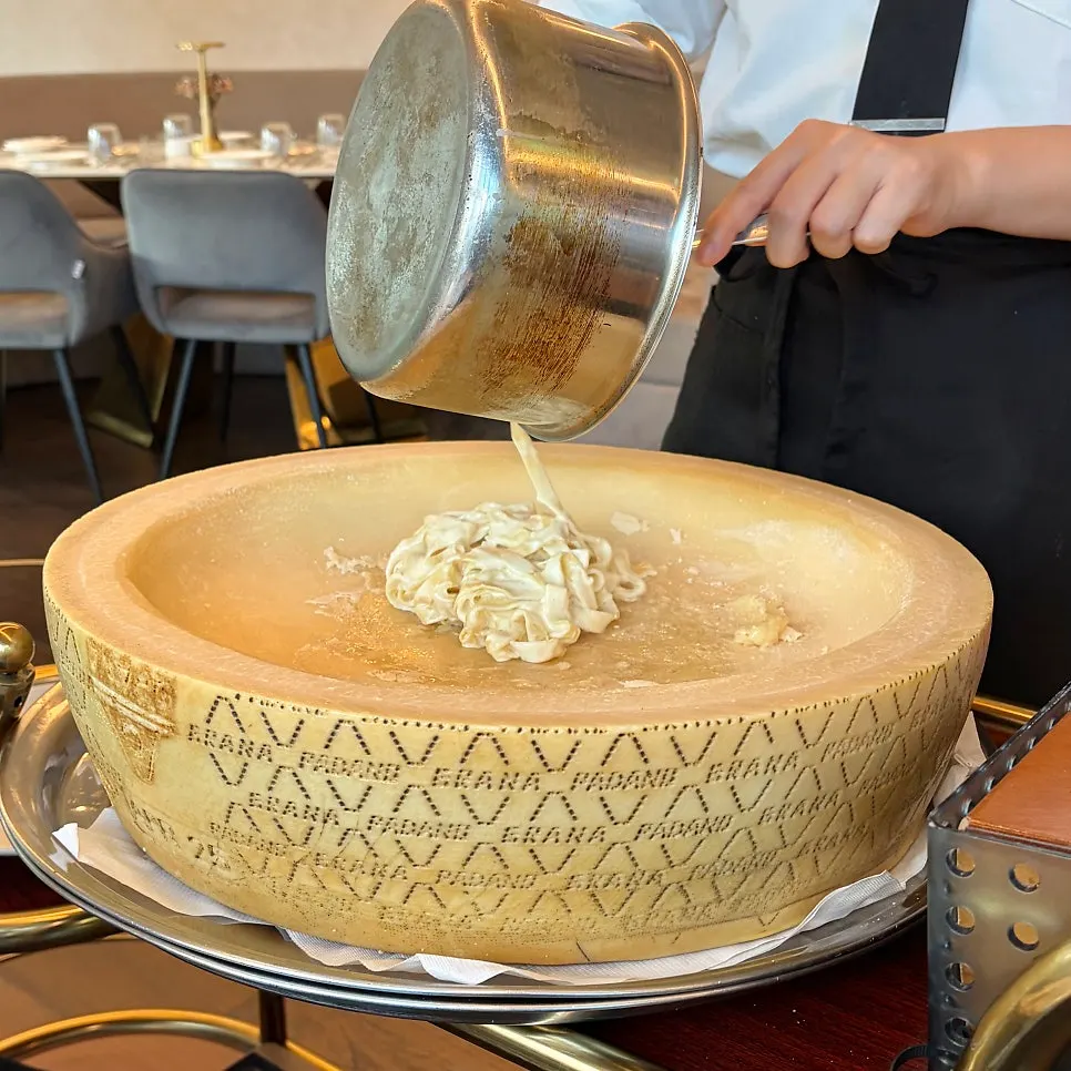 Fresh pasta being mixed into the cheese wheel