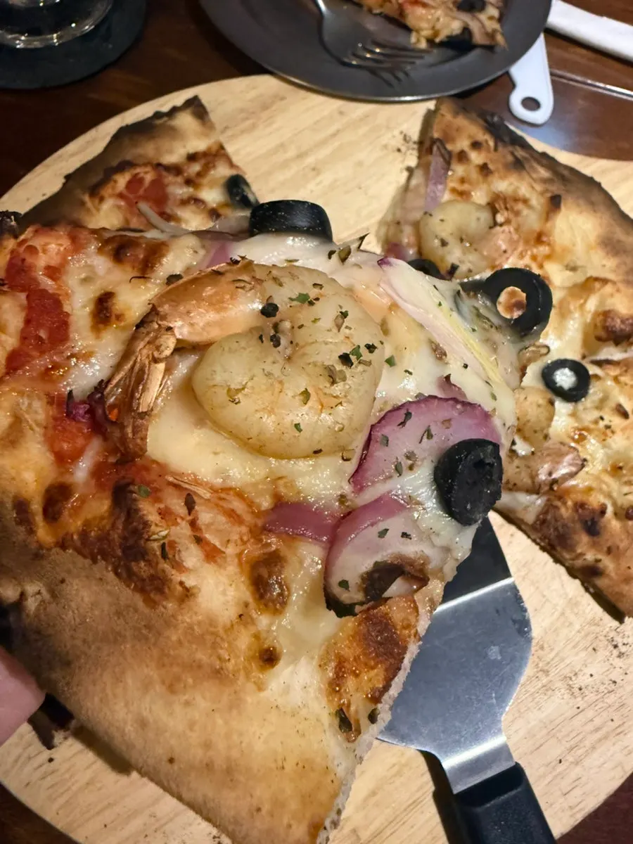 A slice of oven-baked seafood pizza with chewy dough