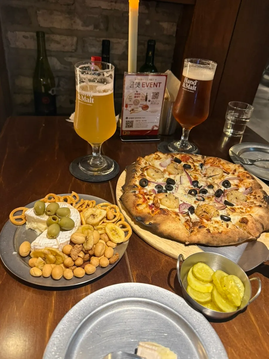 Table set with pizza, brie cheese and beer together