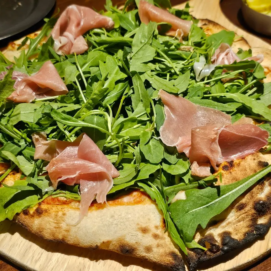 Wood-fired jambon pizza piled high with arugula