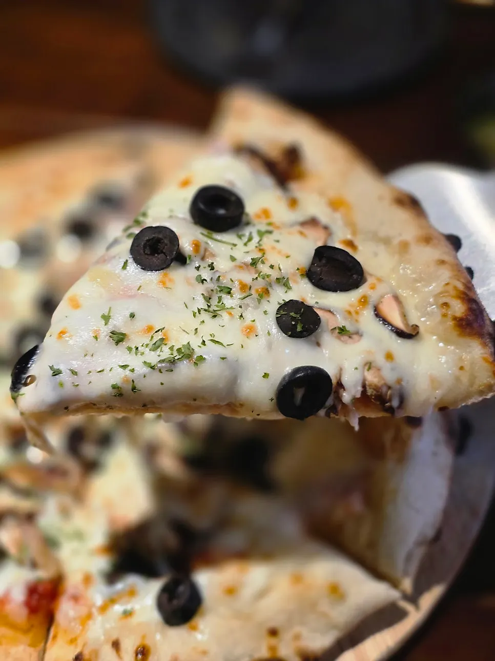 A slice of pizza with cheese and toppings blended together