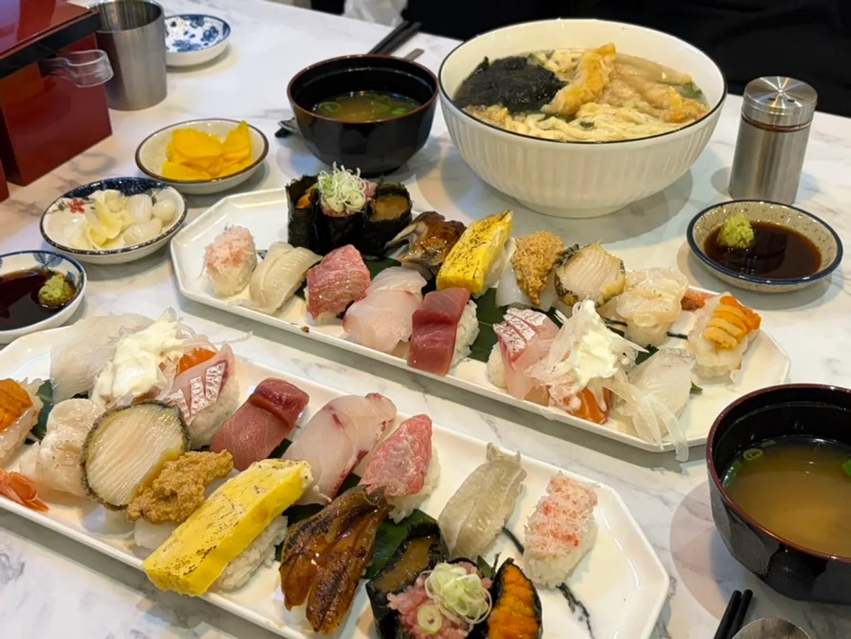 Two plates of premium 17pc sushi with shrimp tempura udon on the table