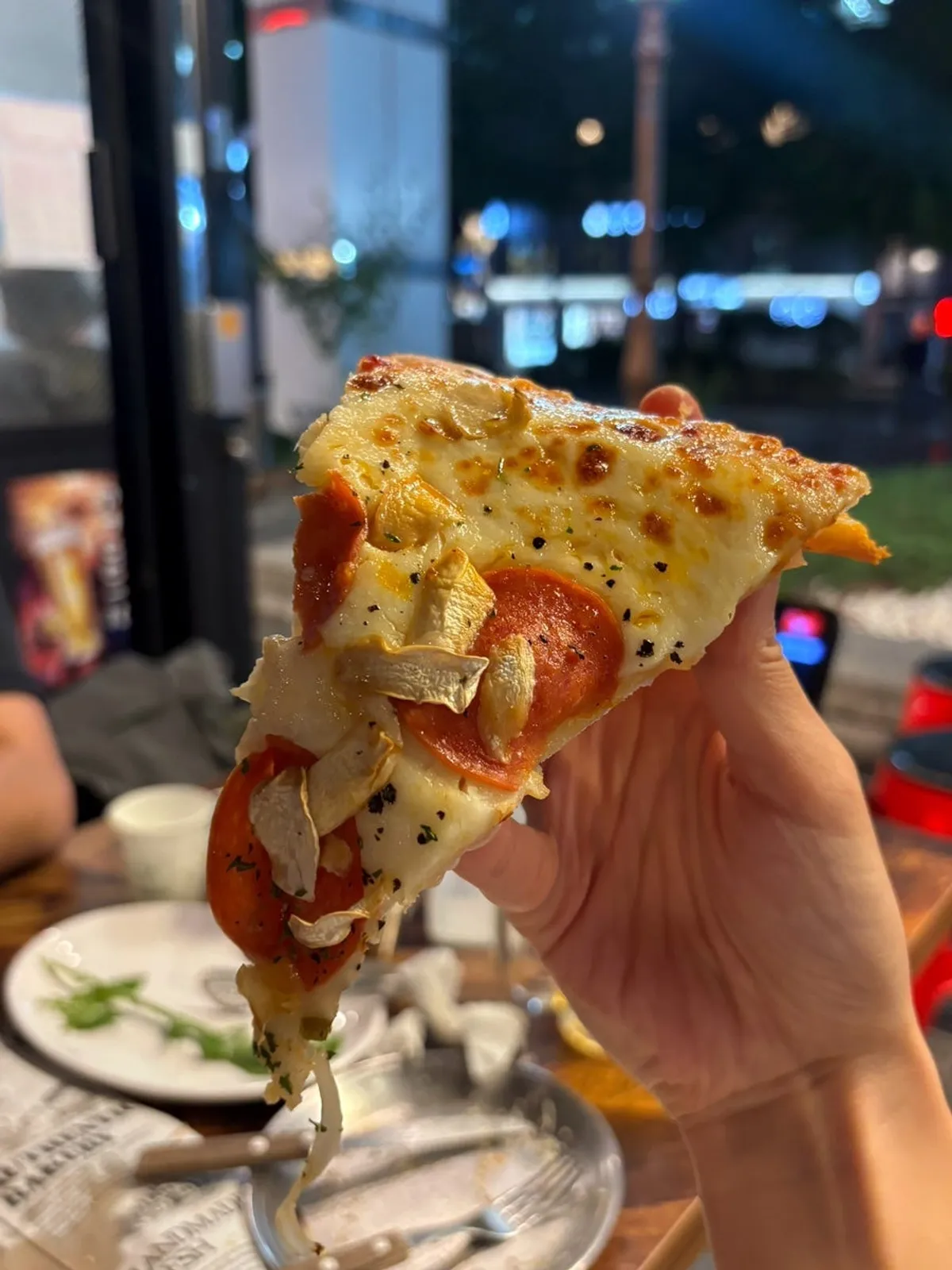 A slice of thin pizza with stretching cheese