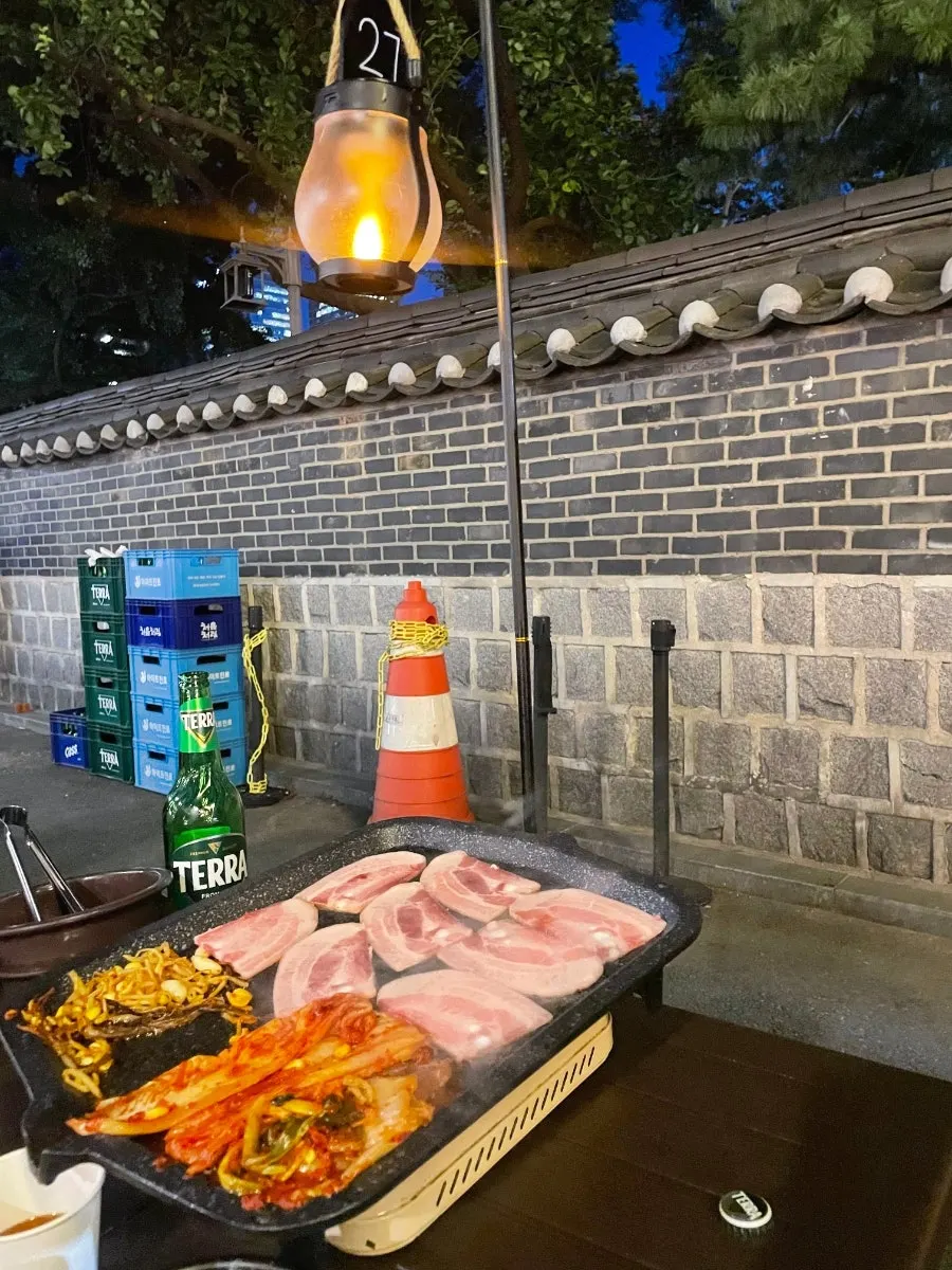 불판에 올린 냉동삼겹살과 김치, 콩나물