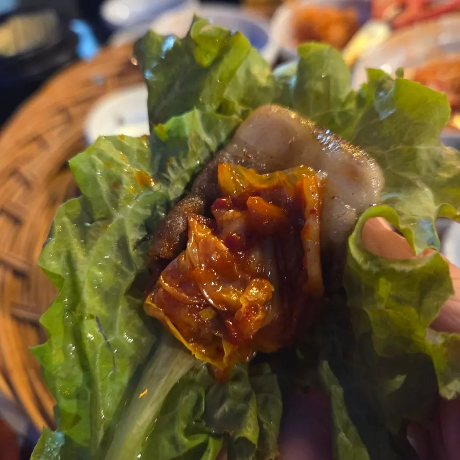 쌈채소에 올린 냉동삼겹살 한 점