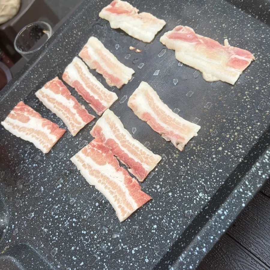 불판 위에서 구워지는 냉동삼겹살과 김치