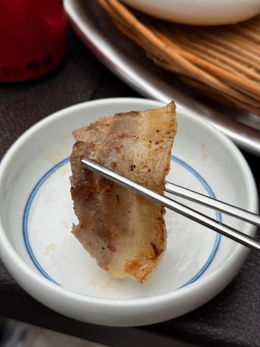 Pork belly grilling in front of the stone wall