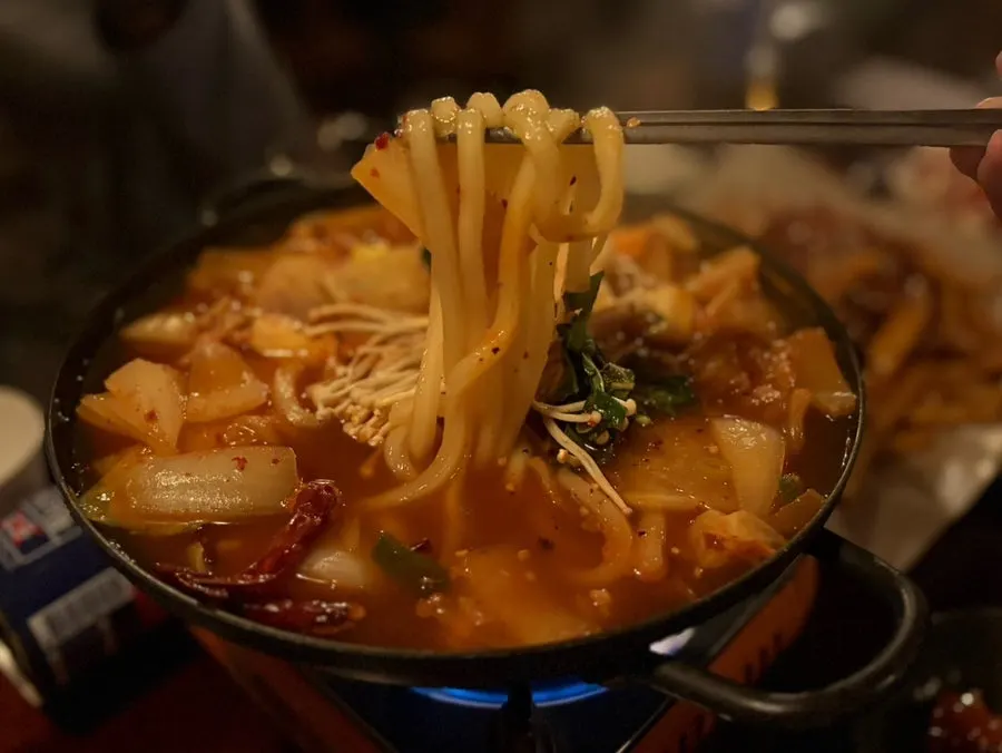 Chicken bites and kimchi udon together on the table