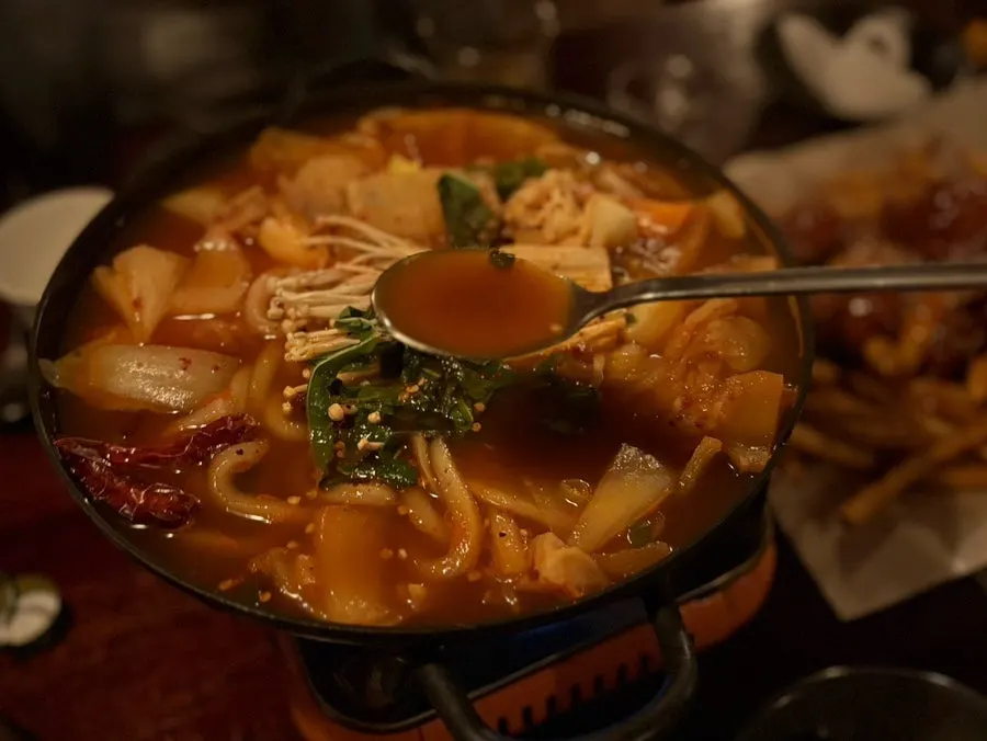 Udon noodles lifted out of the spicy kimchi udon