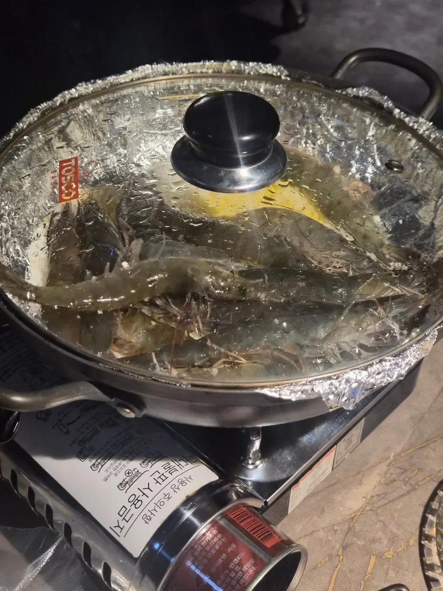 Raw shrimp for salt-grilling served with a burner