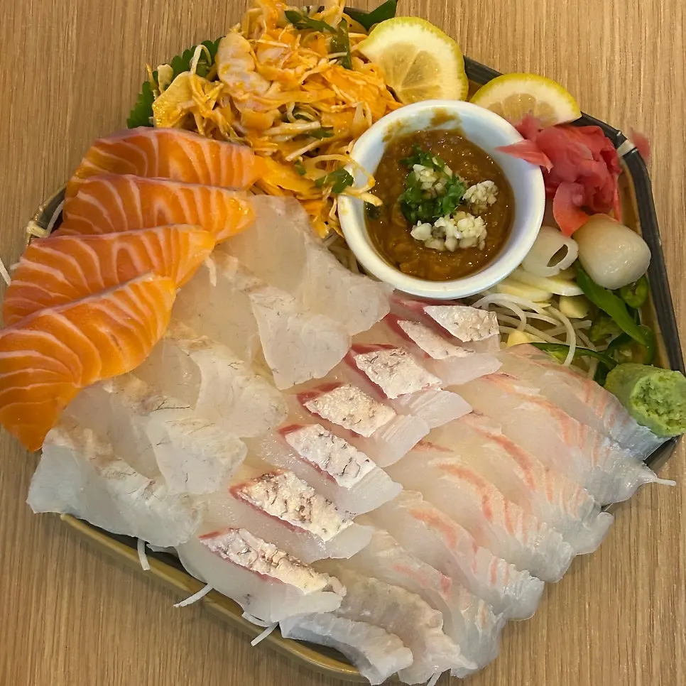 Side dishes including lemon, wasabi, pickled radish, and cabbage salad