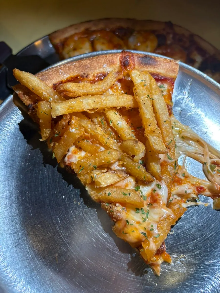 Slice of Potato Killer pizza piled with french fries