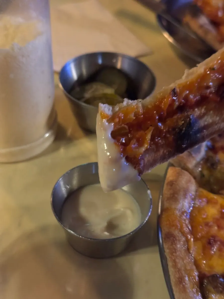 A bitten slice of Shrimp Gangster pizza