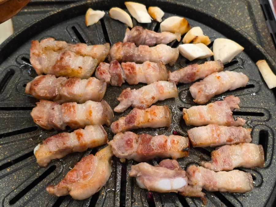 Staff grilling pork belly on the charcoal pan