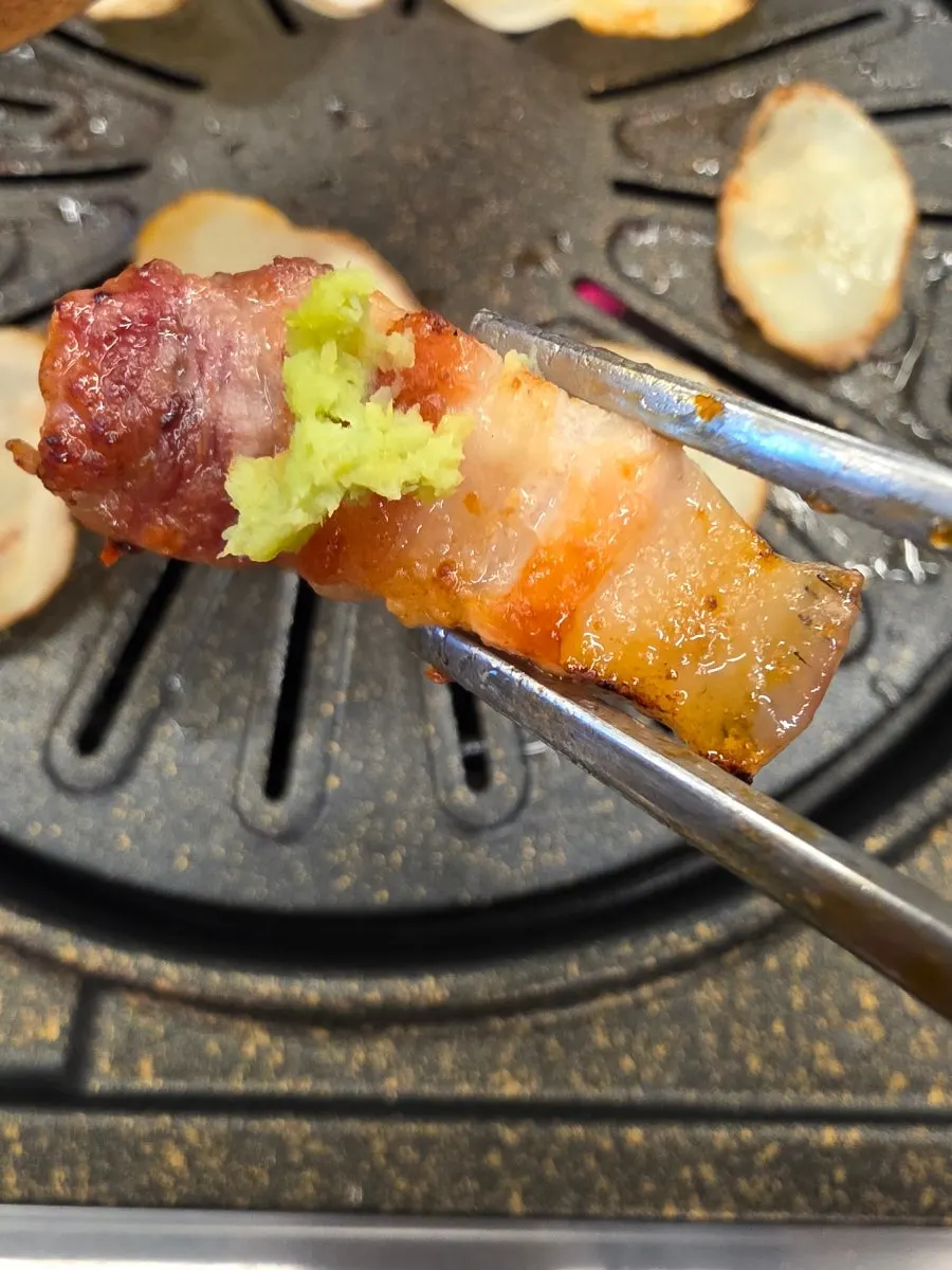 A piece of pork belly placed on a grilled potato slice