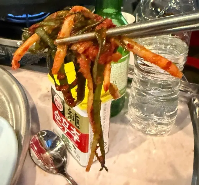 구운 김치와 삼겹살을 함께 집은 젓가락