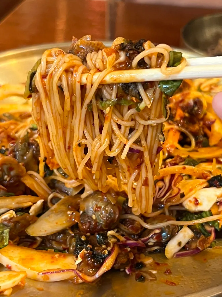 Cockle bibim somyeon eaten alongside the fried jokbal