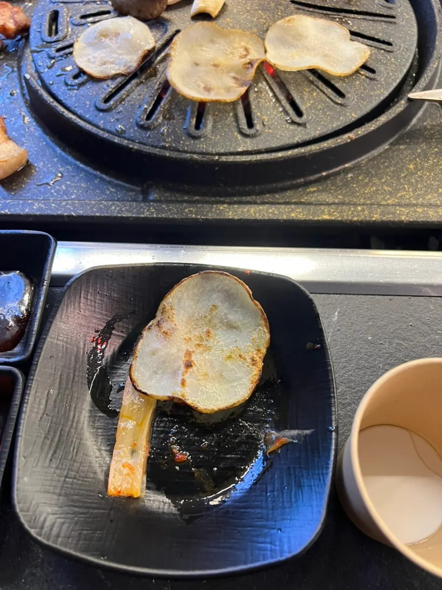 A bite of kimchi and minari grilled in pork fat