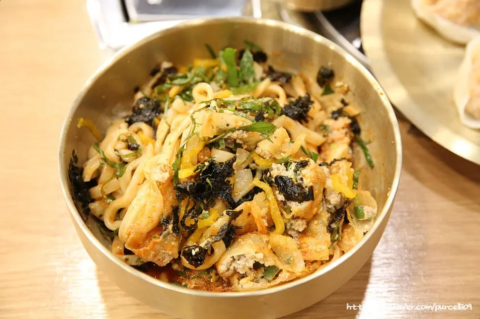 비빔칼국수 위에 올려진 넓적한 만두 두 개