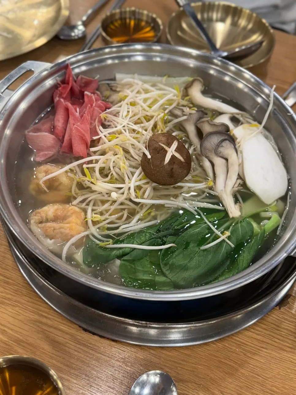 끓는 맑은 육수에 넣은 만두와 채소