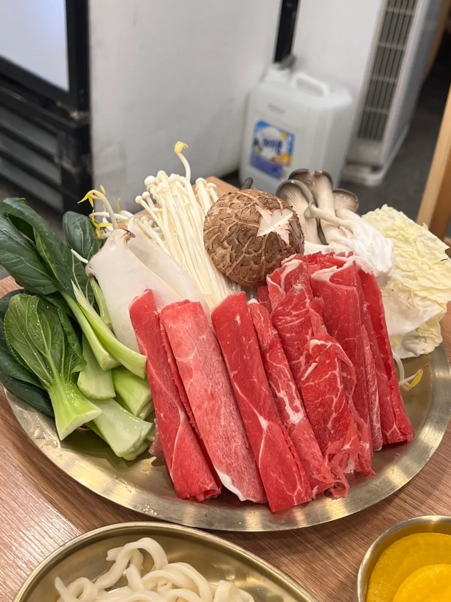 Table setup with clear and spicy broth split half-and-half in the mandu hot pot