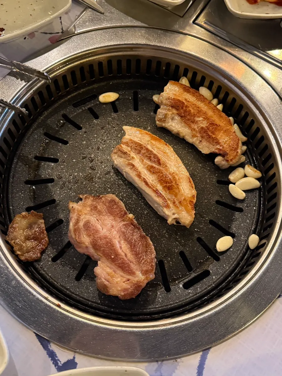 Thickly sliced meat grilling alongside garlic