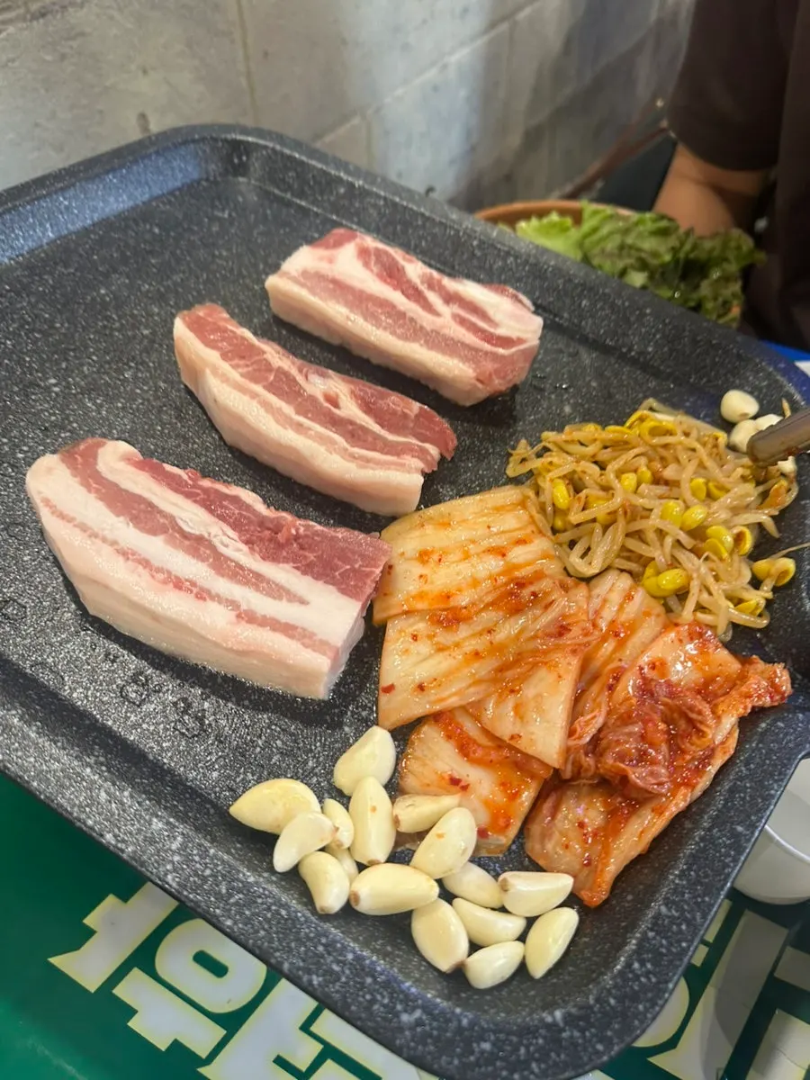 Pork belly, kimchi, bean sprouts, and garlic on the grill plate