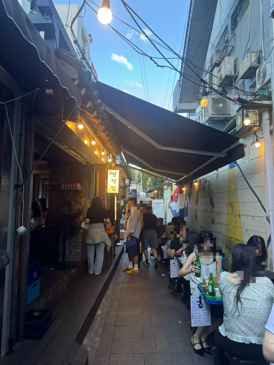 익선동 골목 안 노란 조명이 켜진 멍석집 외관