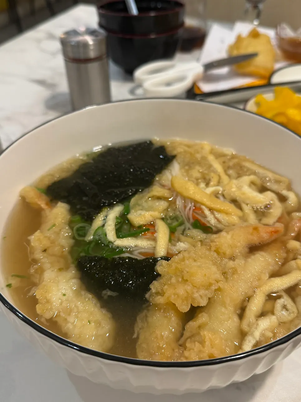 A bowl of udon topped with shrimp tempura