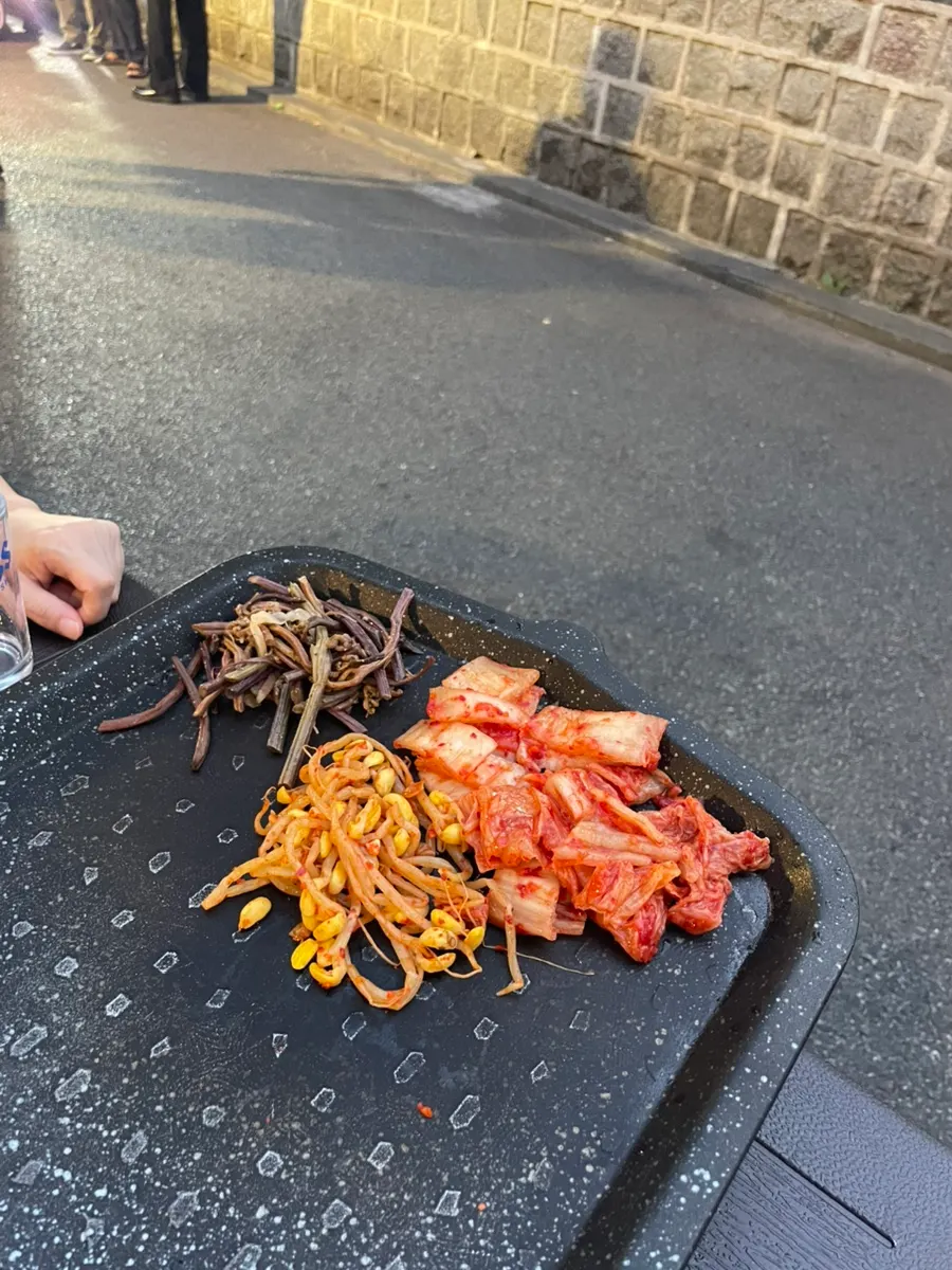 Bracken, kimchi, and bean sprouts placed on the edge of the pan
