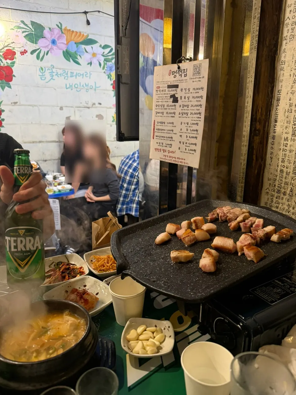 Table at Meongseokjip with grilled meat and self-serve bar side dishes