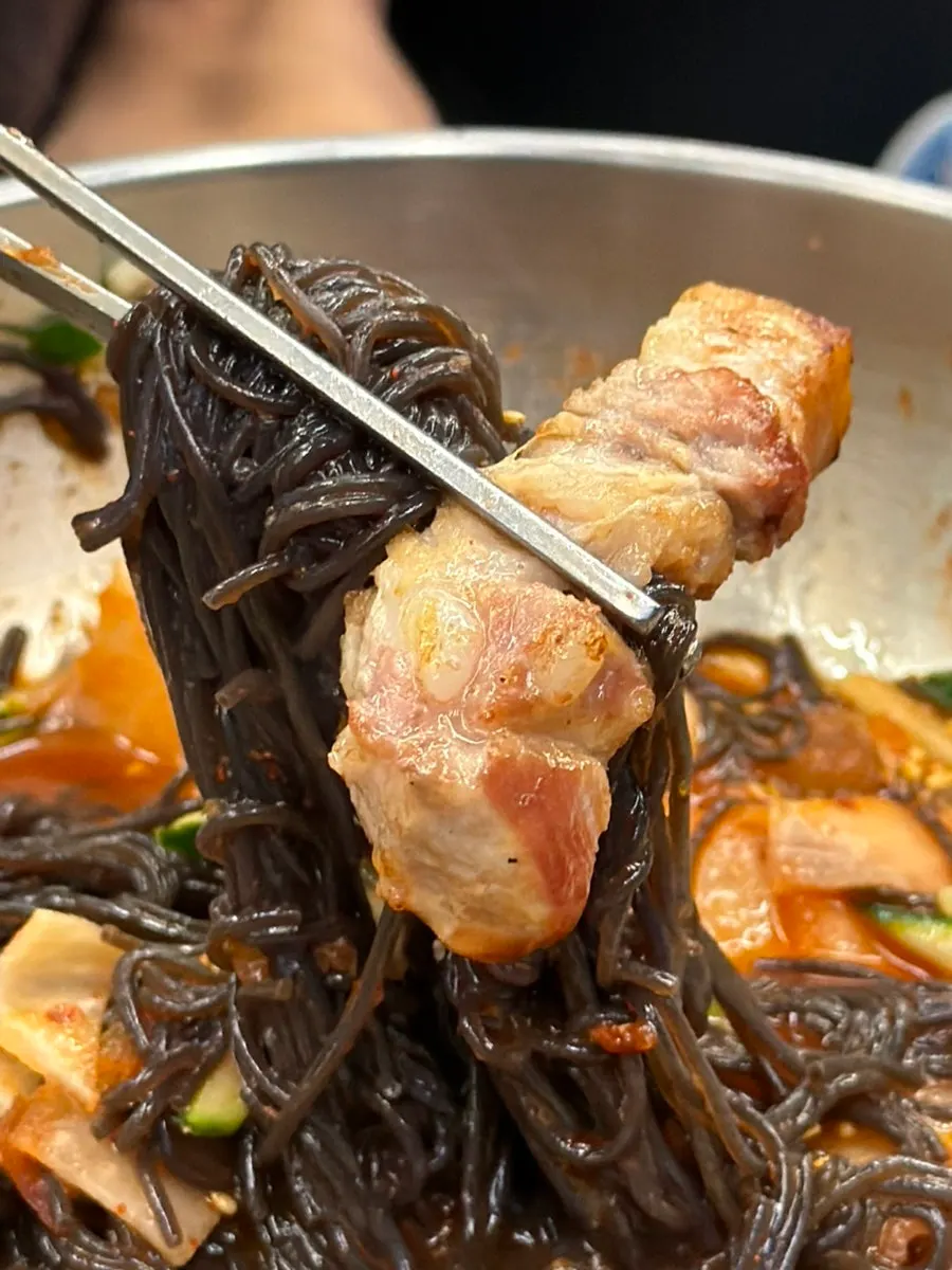 A bite of meat with grilled kimchi and minari