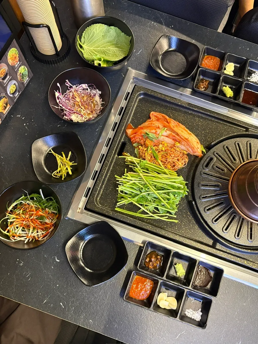 Basic side dishes of kimchi, seasoned bean sprouts, and minari at Cham Dwaejitgan