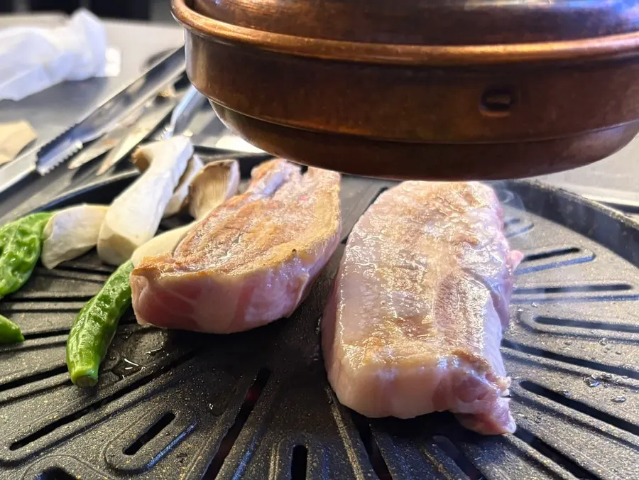Staff grilling pork belly at Cham Dwaejitgan