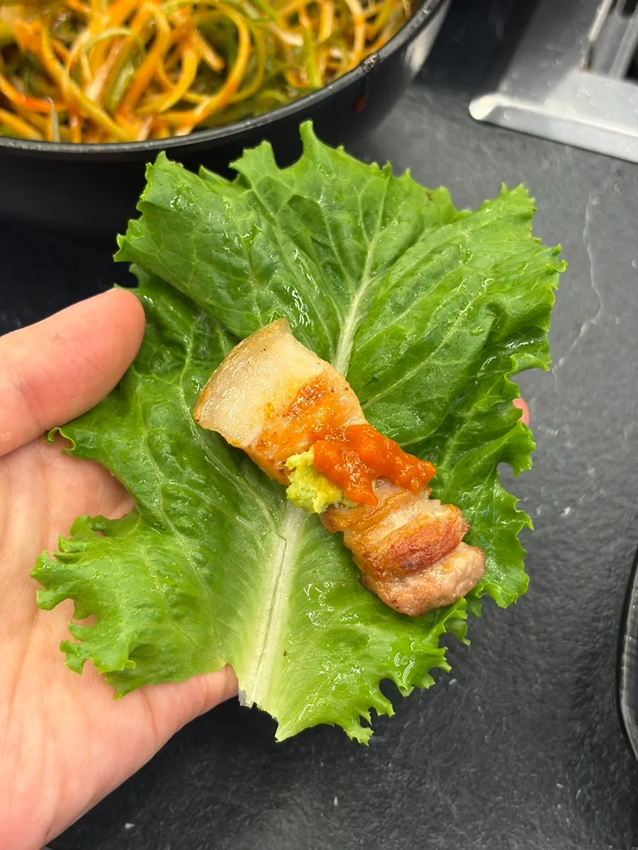 구운 미나리를 올린 삼겹살 한 점