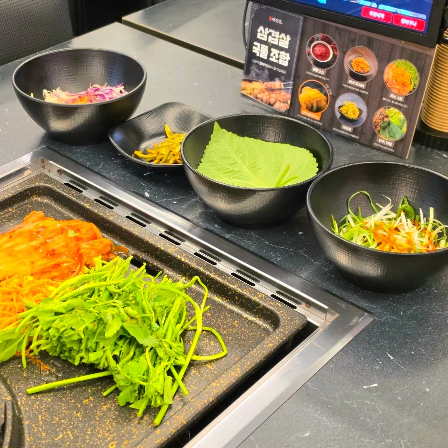 Kimchi, bean sprouts, and minari placed on one side of the grill