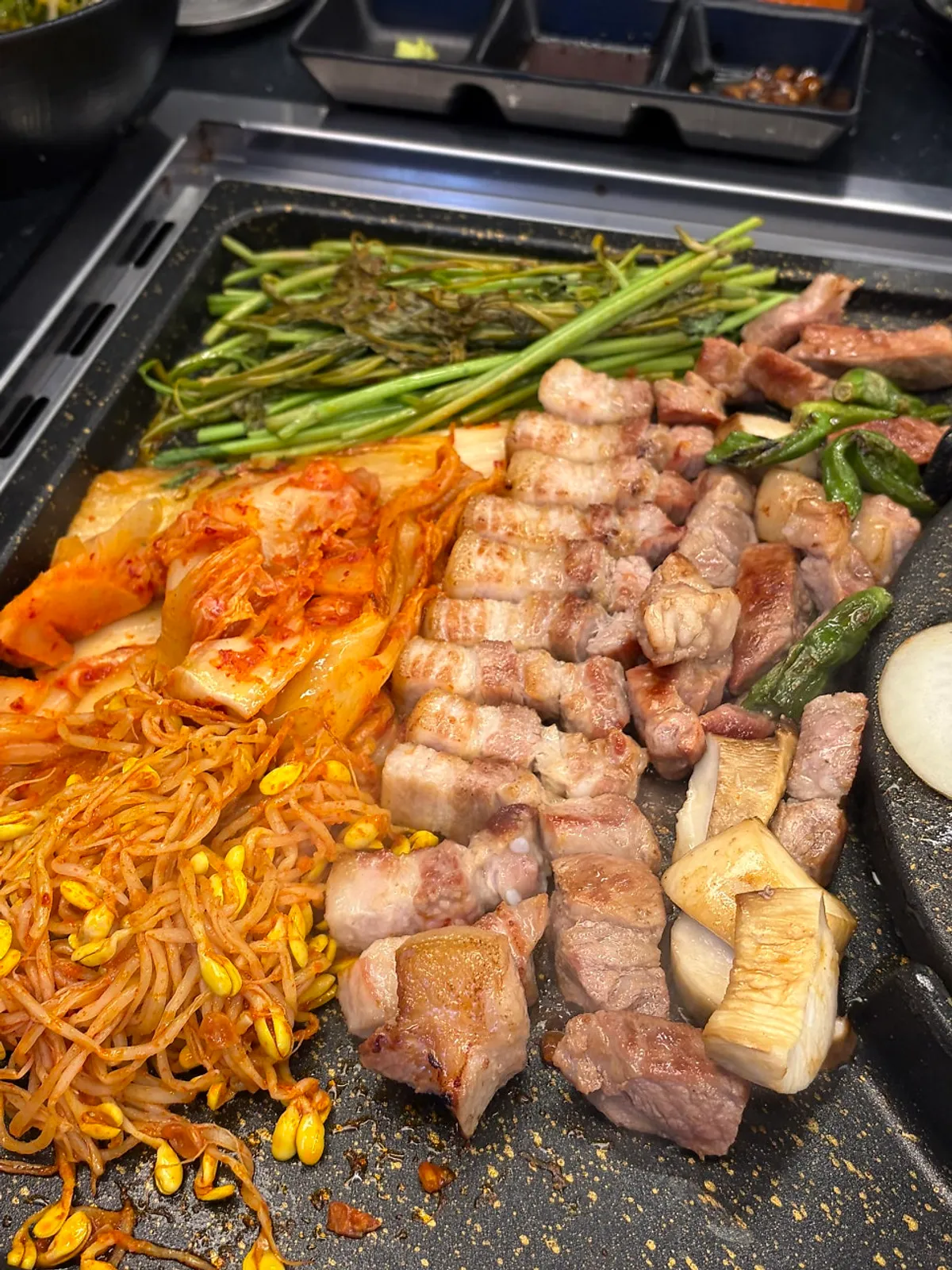 Fully cooked pork belly and potato slices moved down the grill