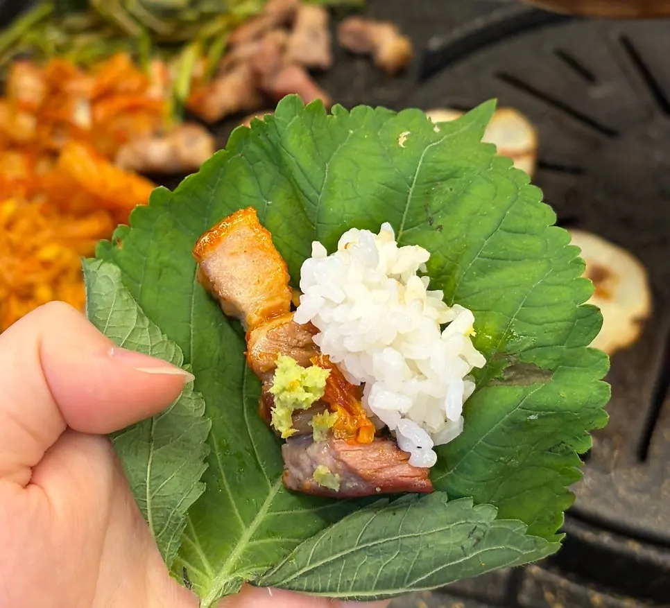 Perilla leaf wrap topped with grilled kimchi and minari