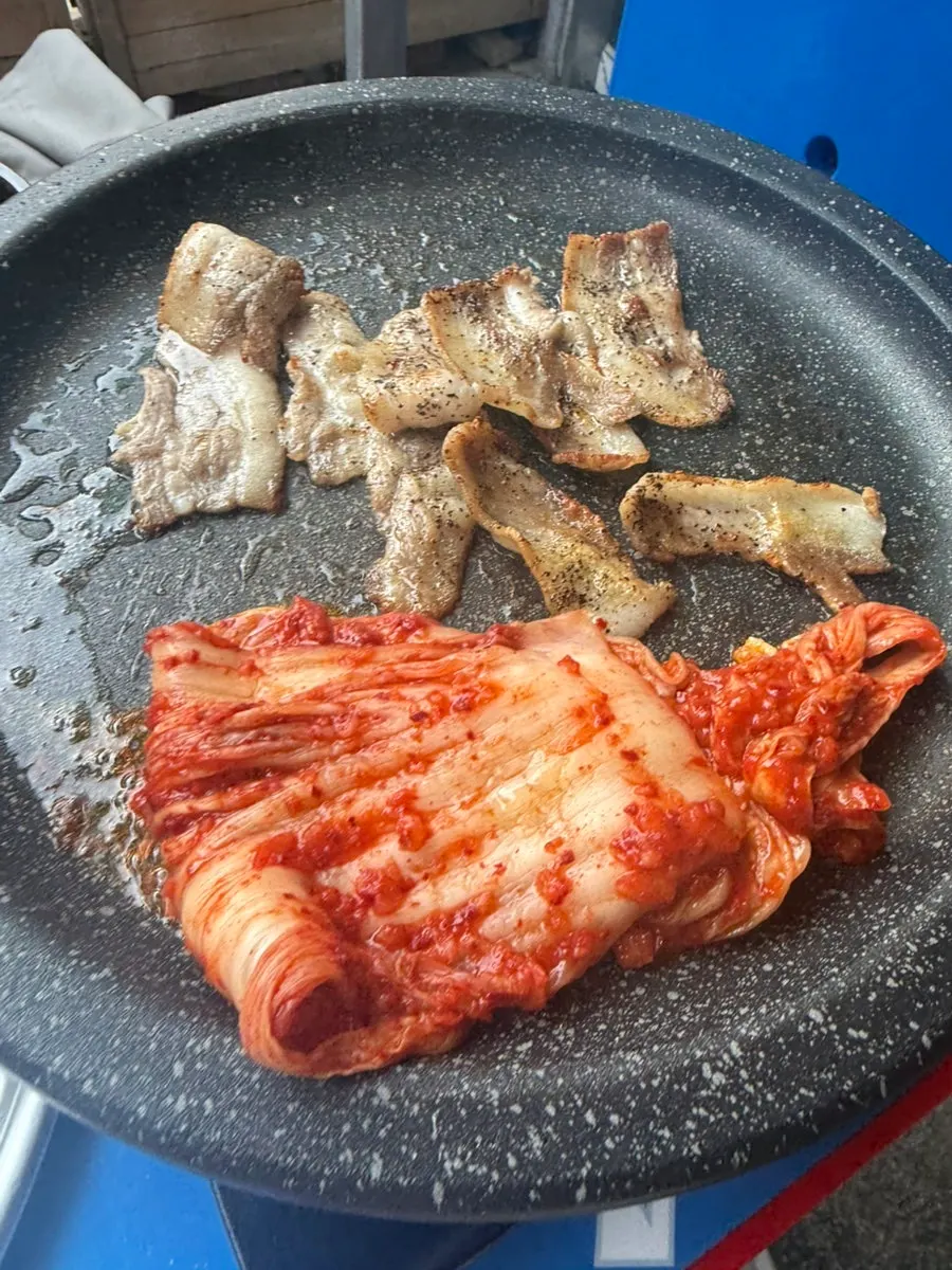 Kimchi and bean sprouts added to the grill alongside the meat