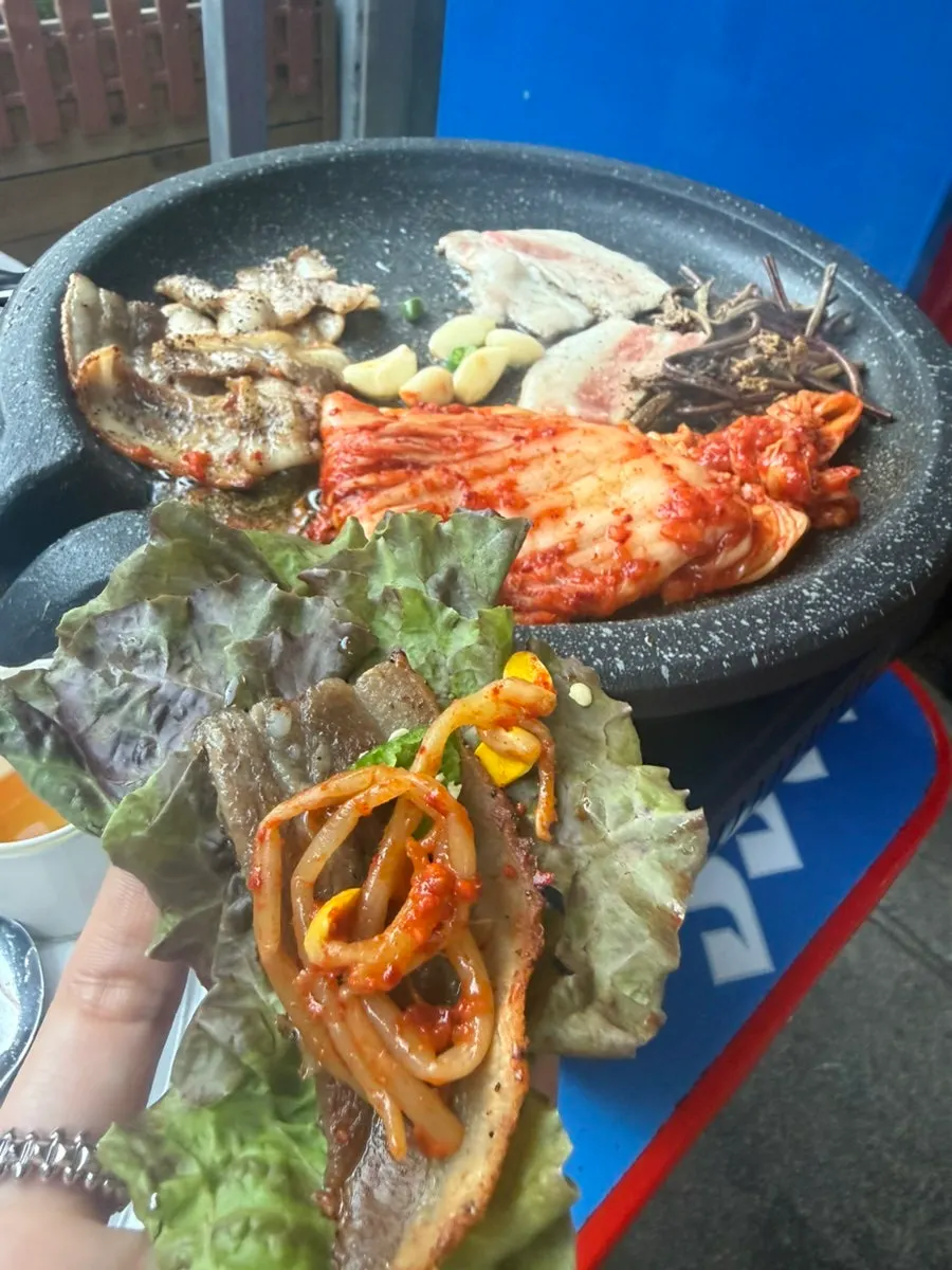 A piece of pork belly and kimchi on a lettuce leaf