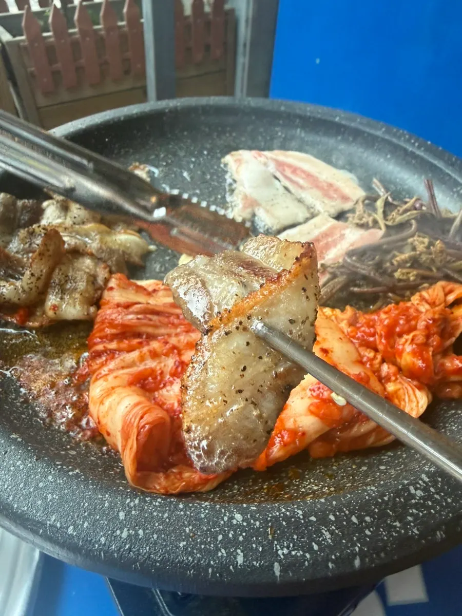 Meat, kimchi, and bean sprouts grilling together on the outdoor BBQ grill