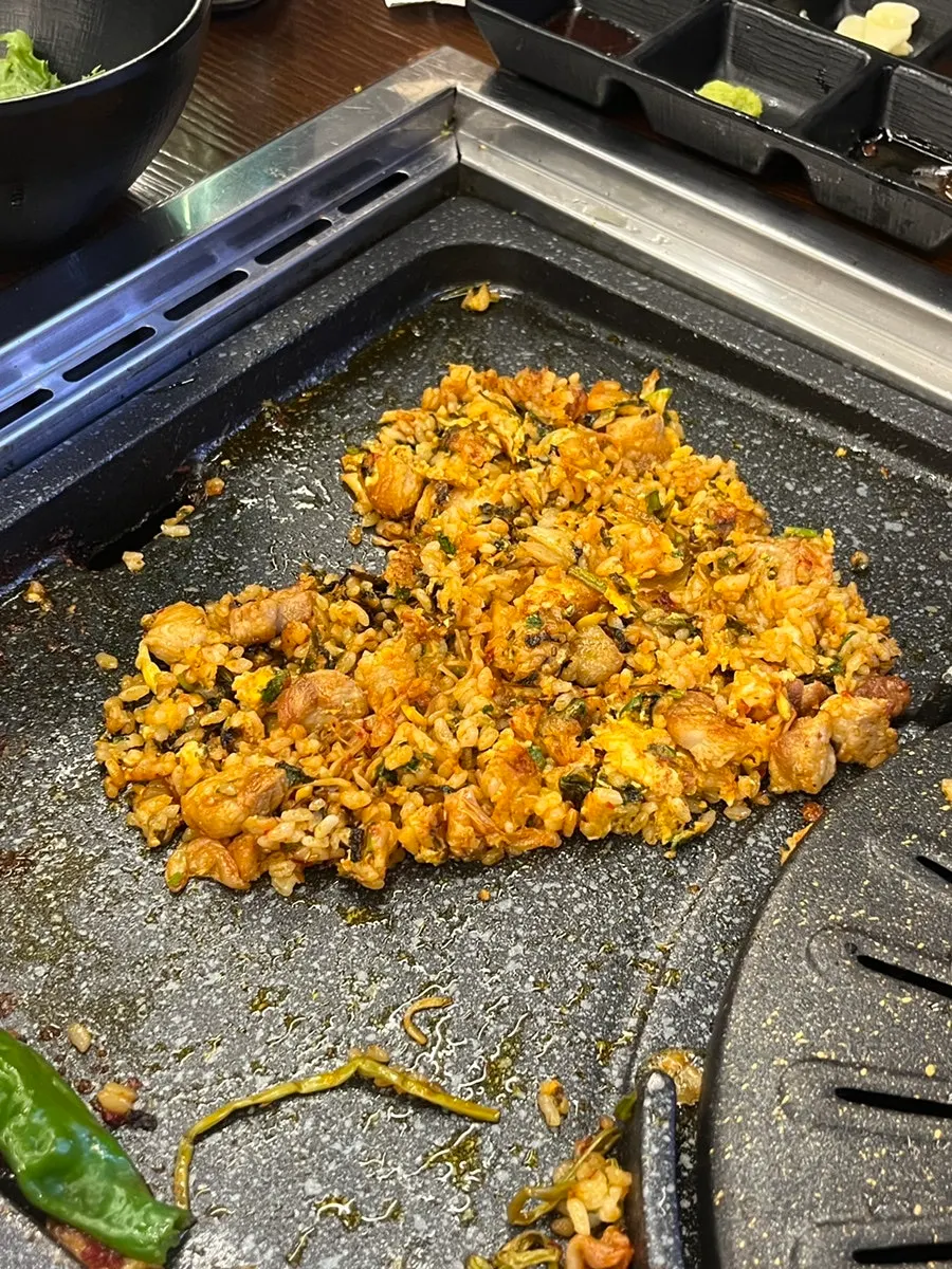 Fried rice being cooked tableside on the grill to finish the meal