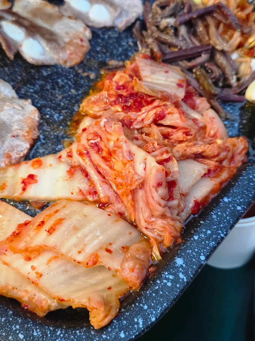 Kimchi and bracken fern cooking at the bottom of the grill