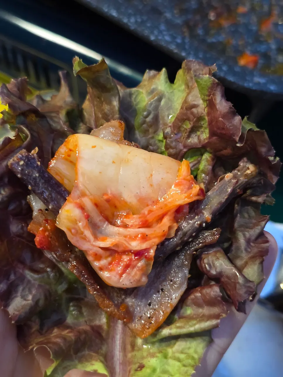 A wrap of frozen pork belly topped with green onion kimchi