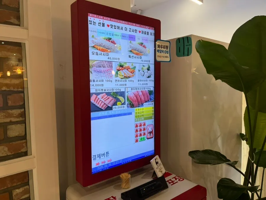 Menu board in front of the restaurant showing sushi, sashimi, and kaisendon