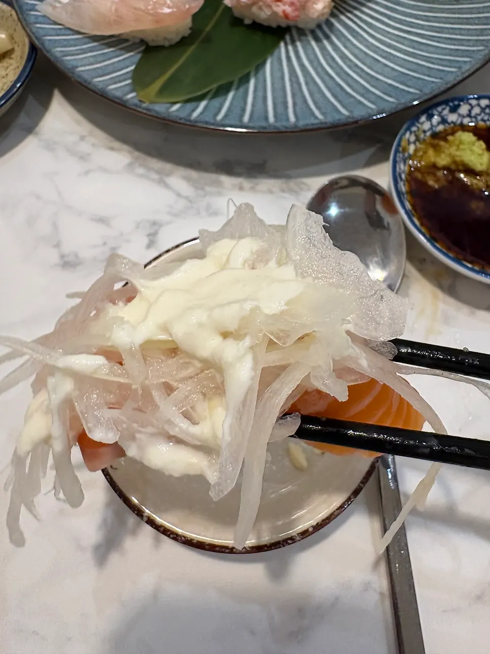 Salmon sushi topped with onion and sauce