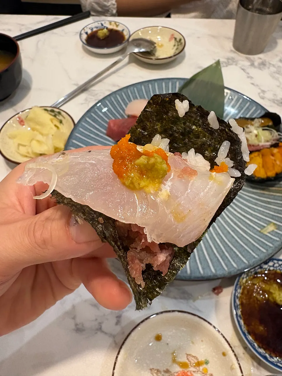 A bite with sashimi and sea urchin roe on seaweed