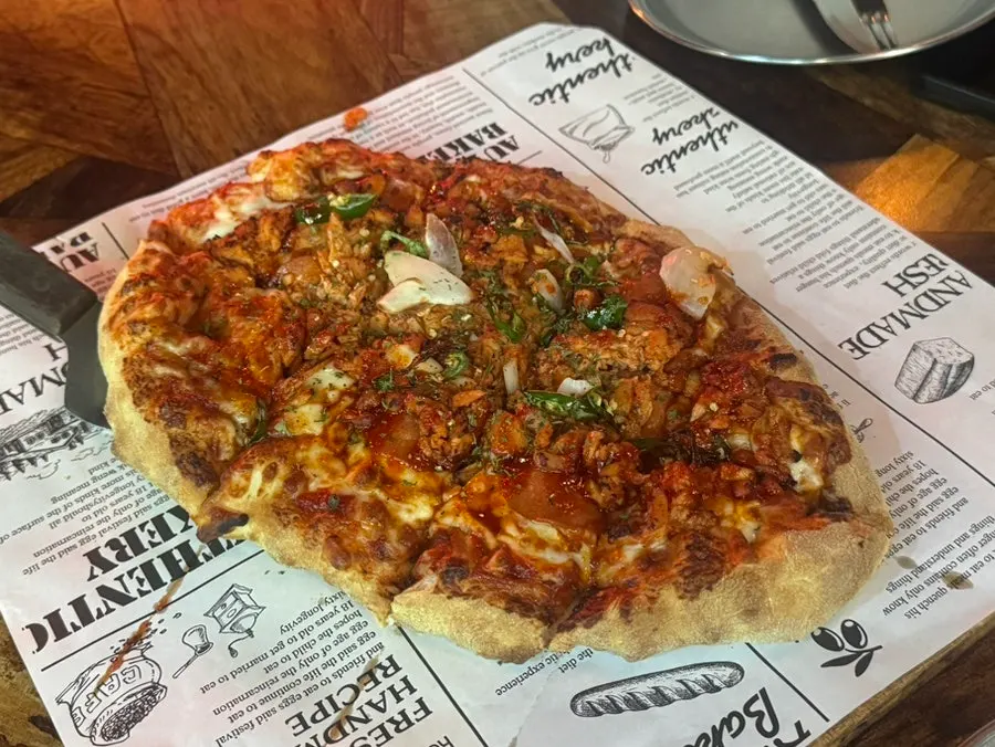 Buldak pizza topped with spicy chicken and fire chicken sauce