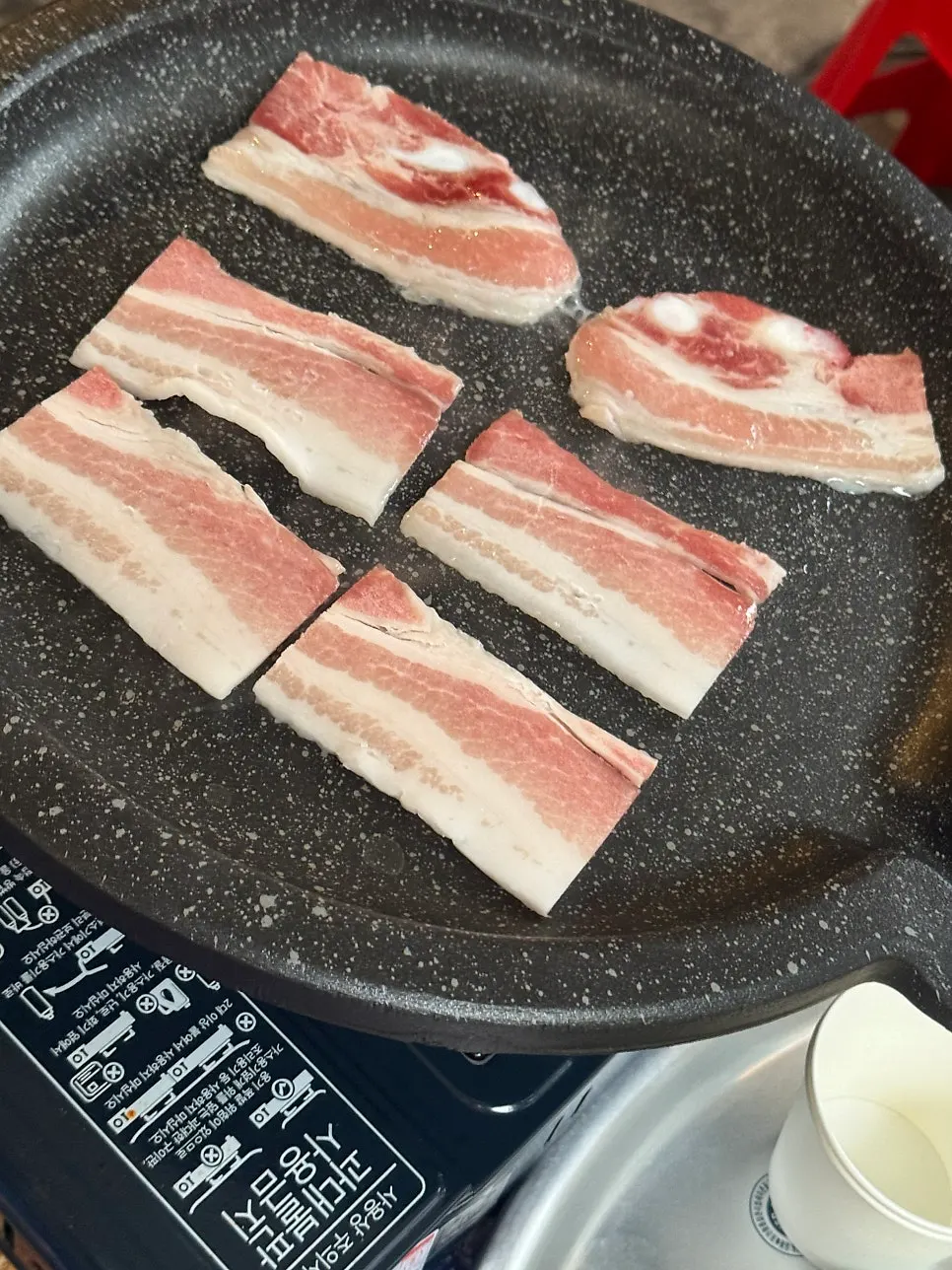 Frozen pork belly cooking on the grill at an outdoor table